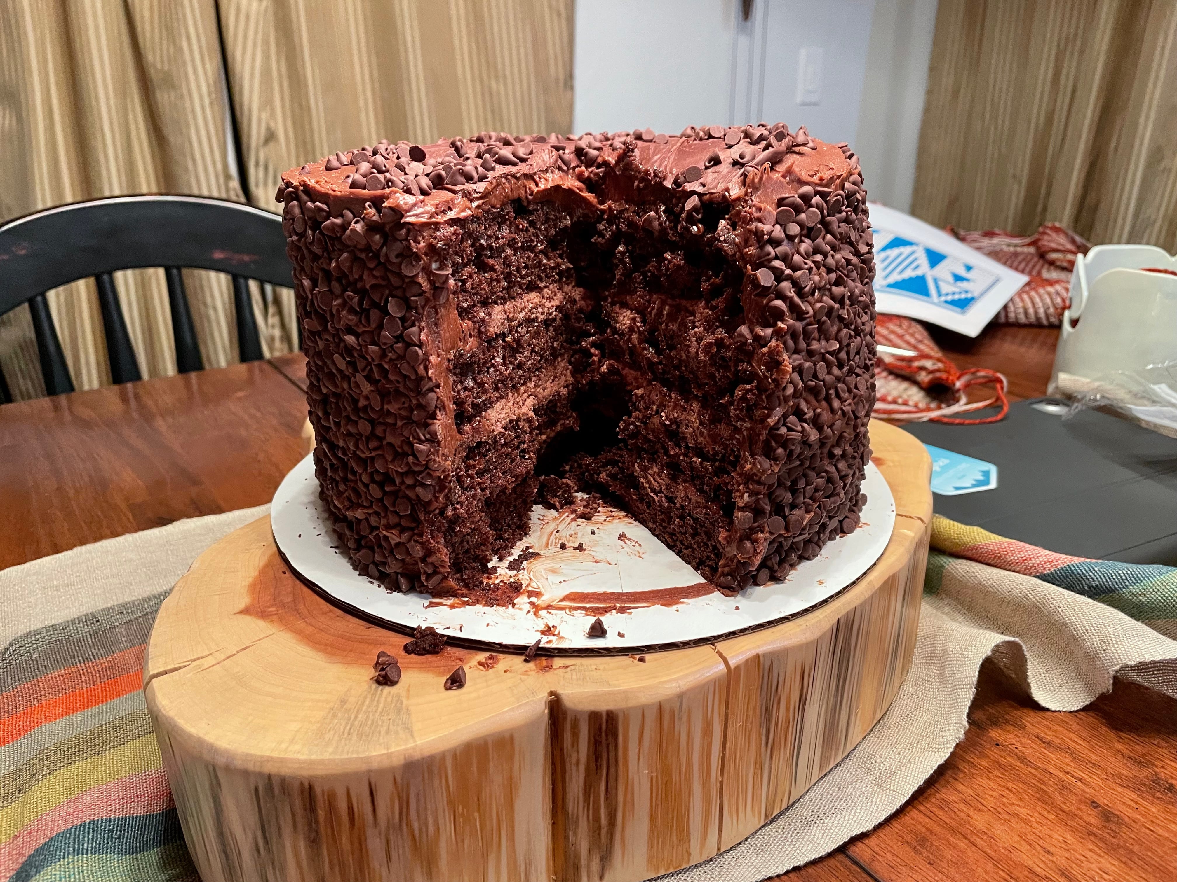 A four layer chocolate cake with miniature chocolate chips covering the sides.