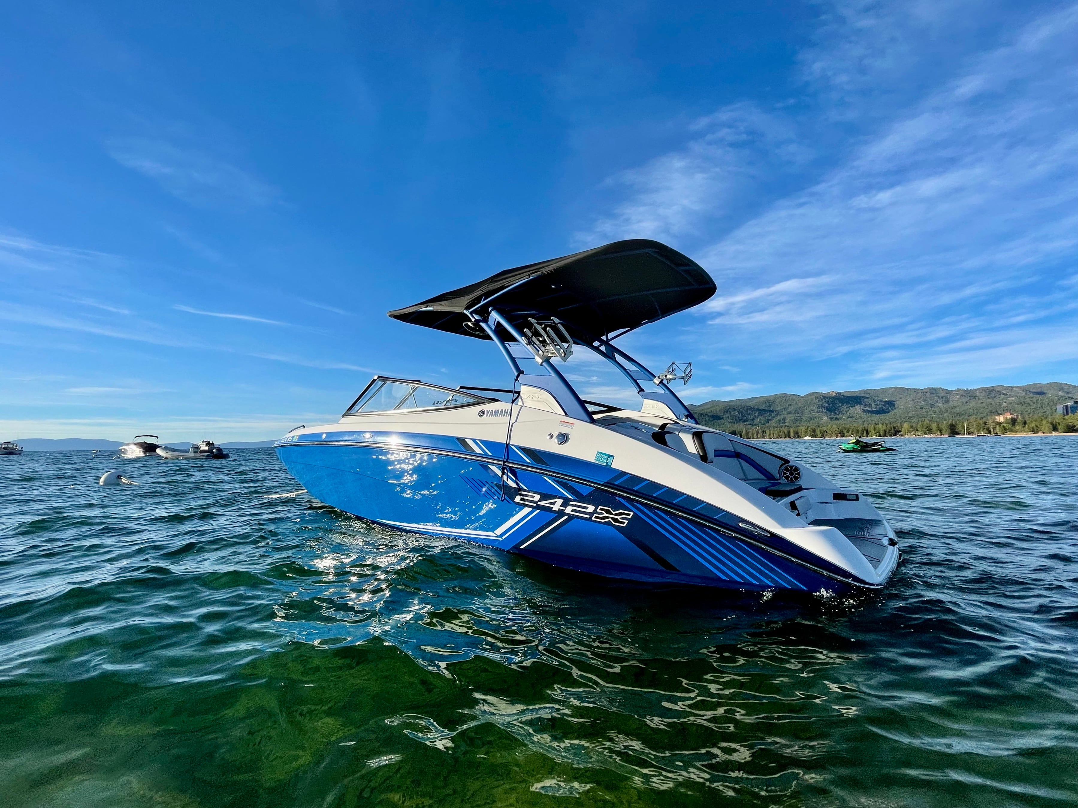 A blue speedboat sitting in green-blue water, with mountains behind it.