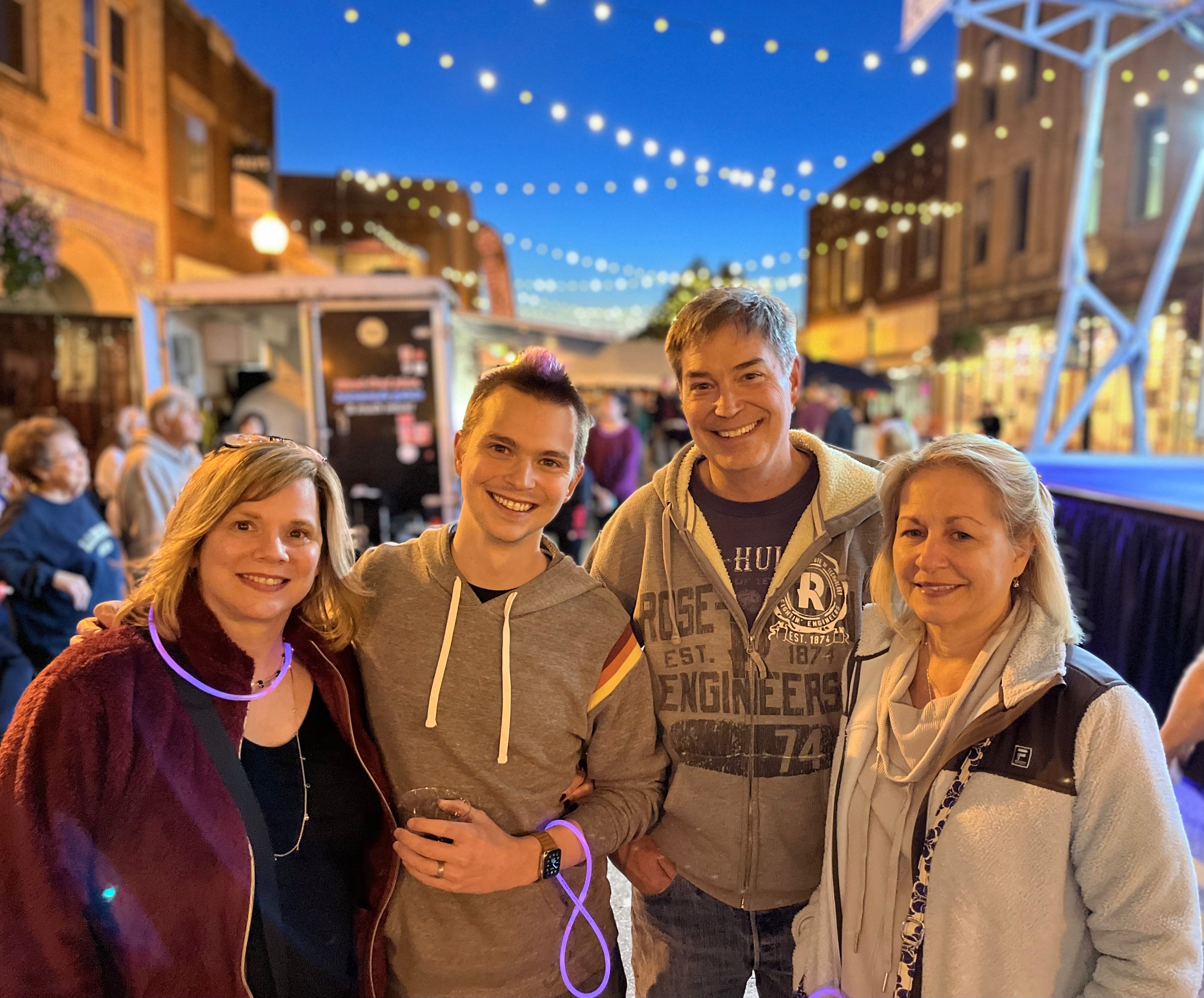 Four people posing for a photo at a street fair.