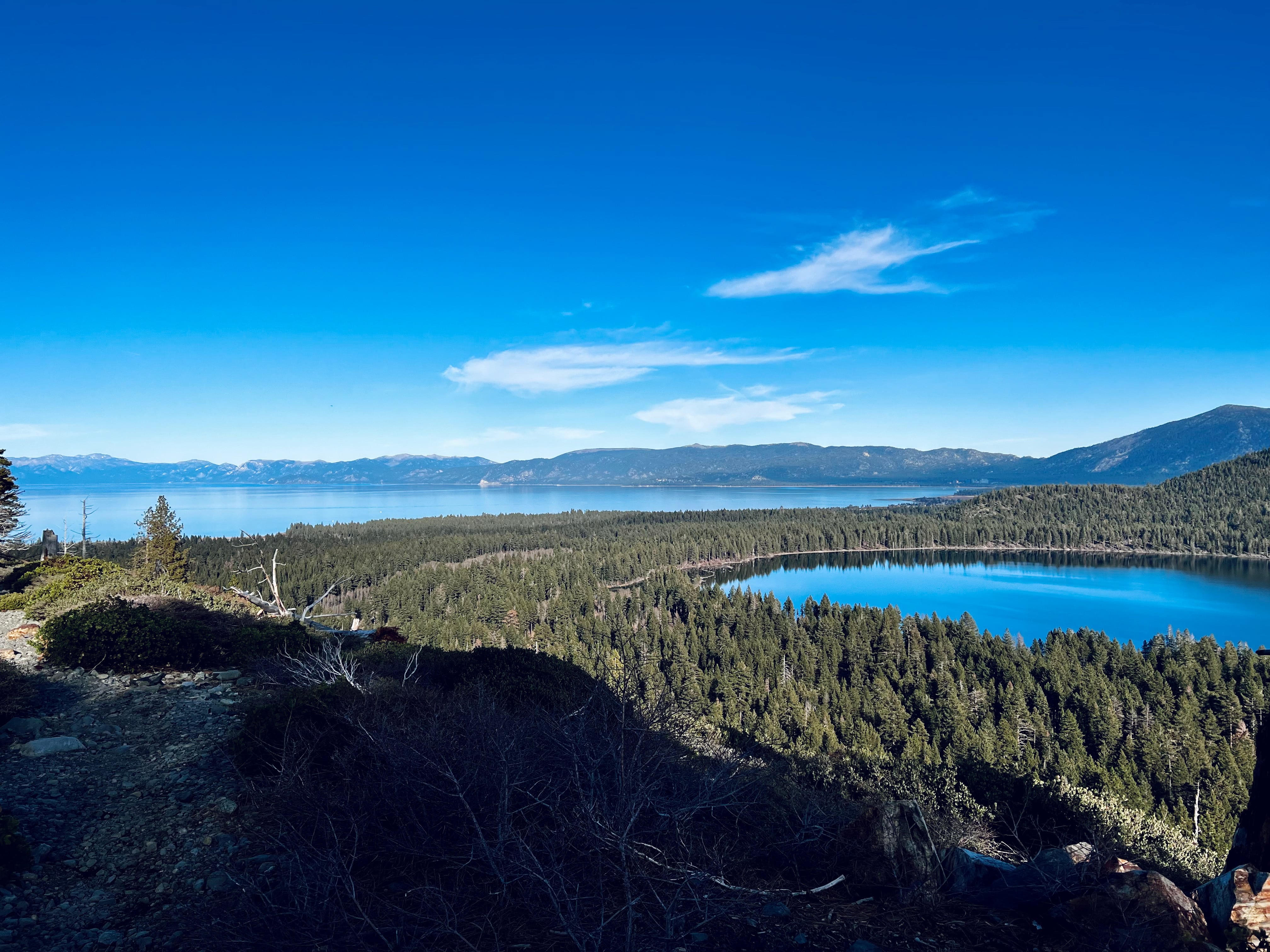 A view from a mountain ridge looking out onto lakes, trees, and other moutains.