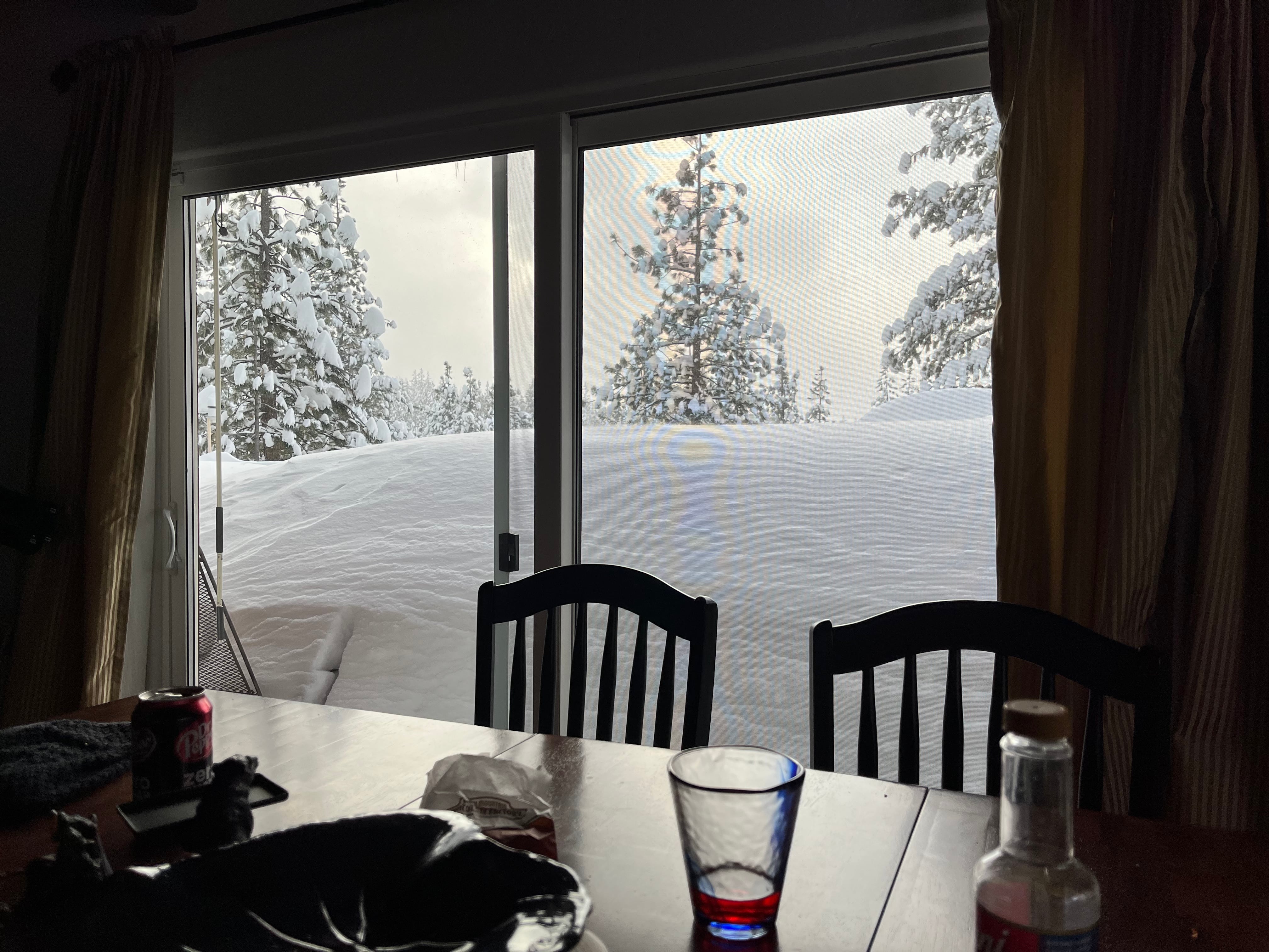 Photo from inside a house looking through a sliding glass door. Outside a huge amount of snow obscures all else.