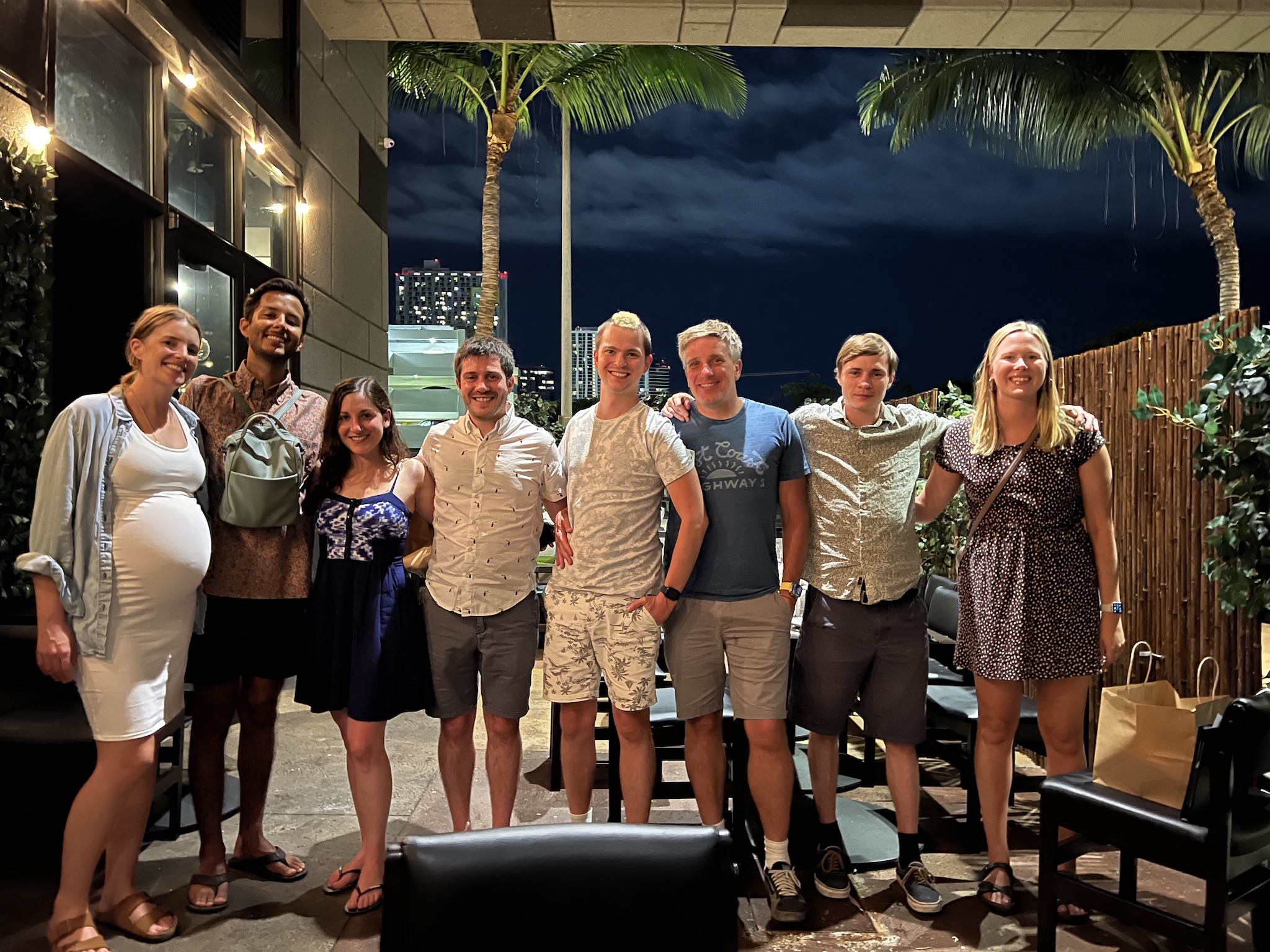 A line of people posing for a photo. Myke and James are in the middle.