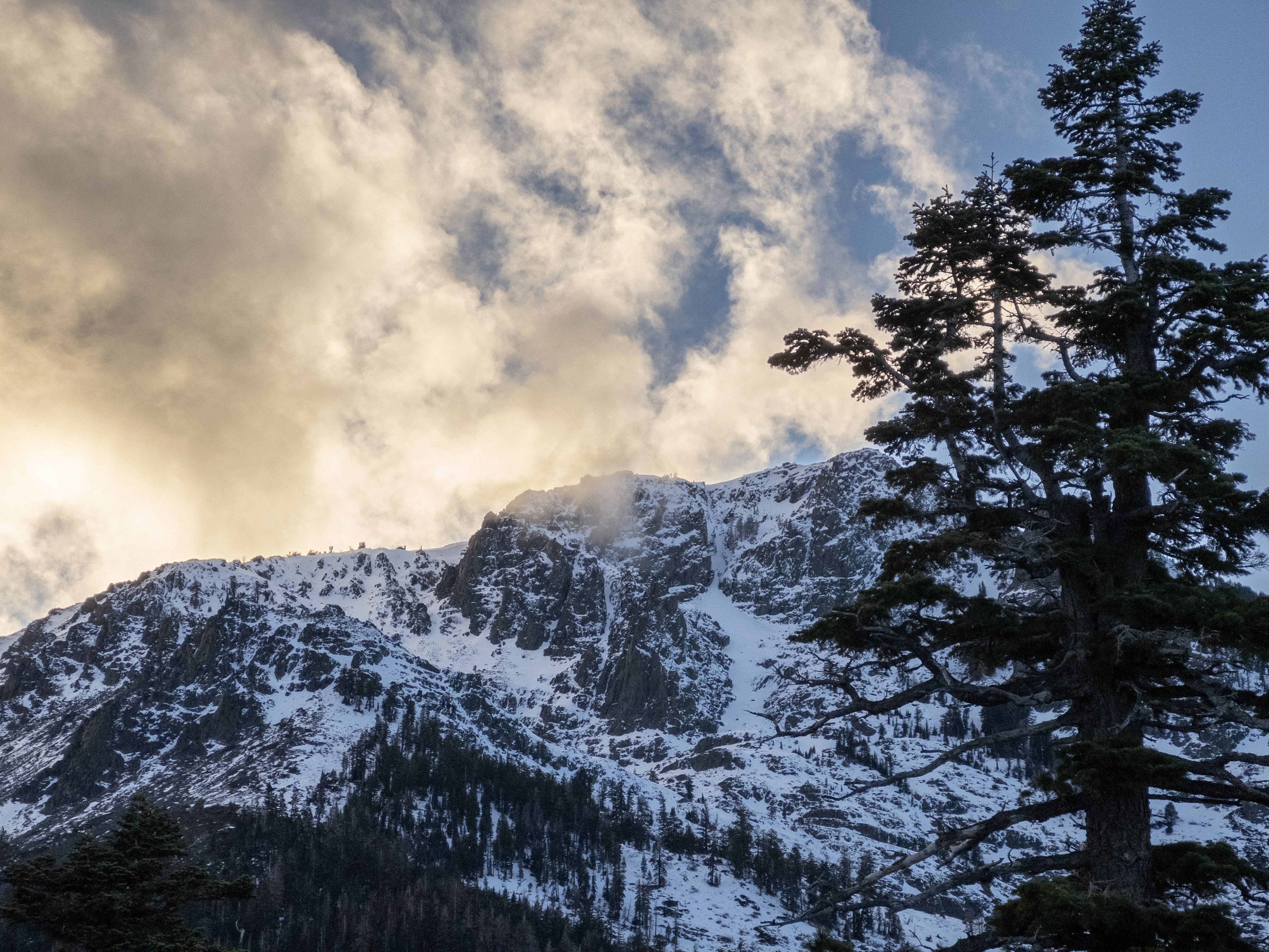 Clouds coming over the top of a mountain