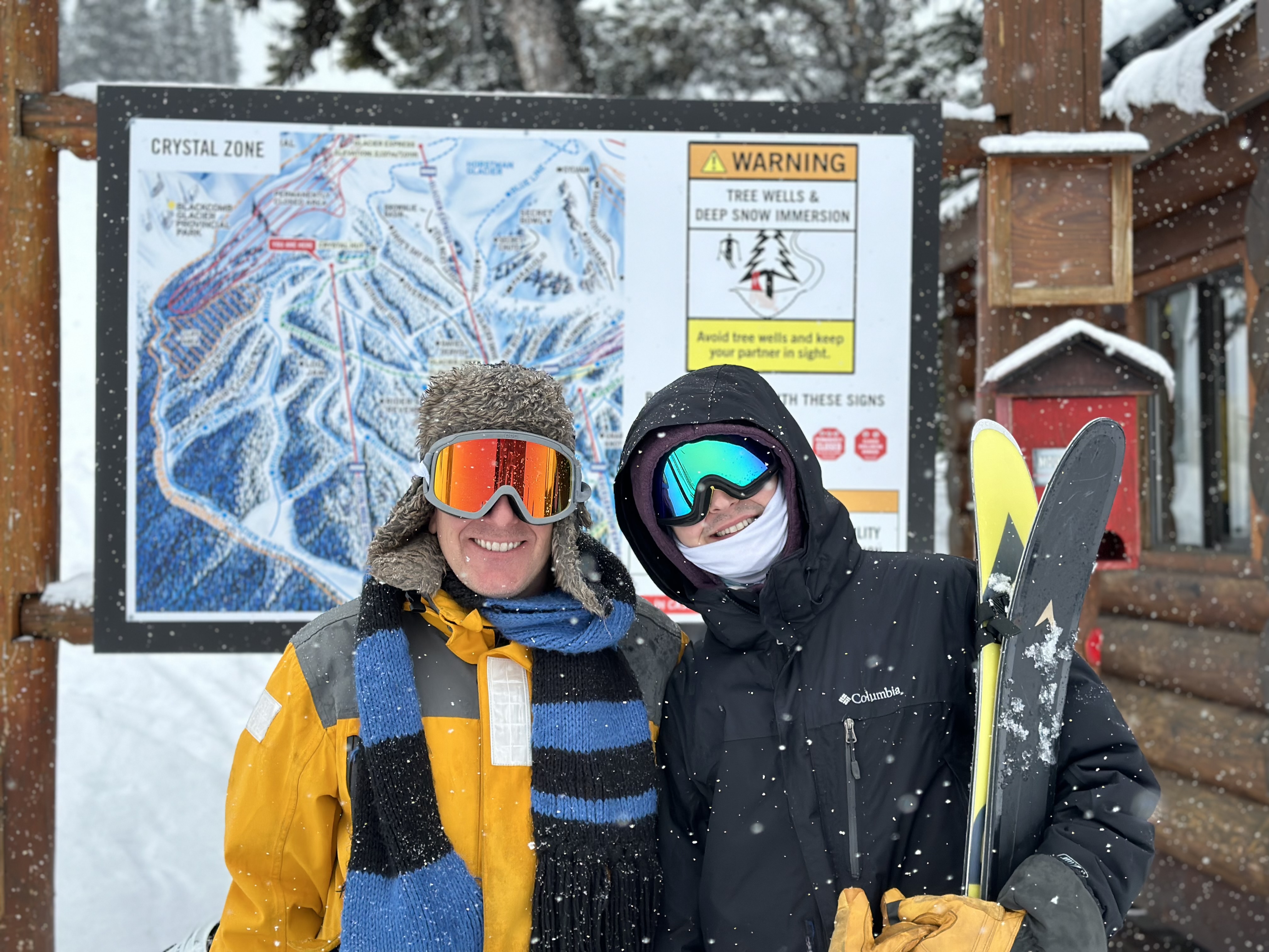 Two people standing in front of a mountain trail map.