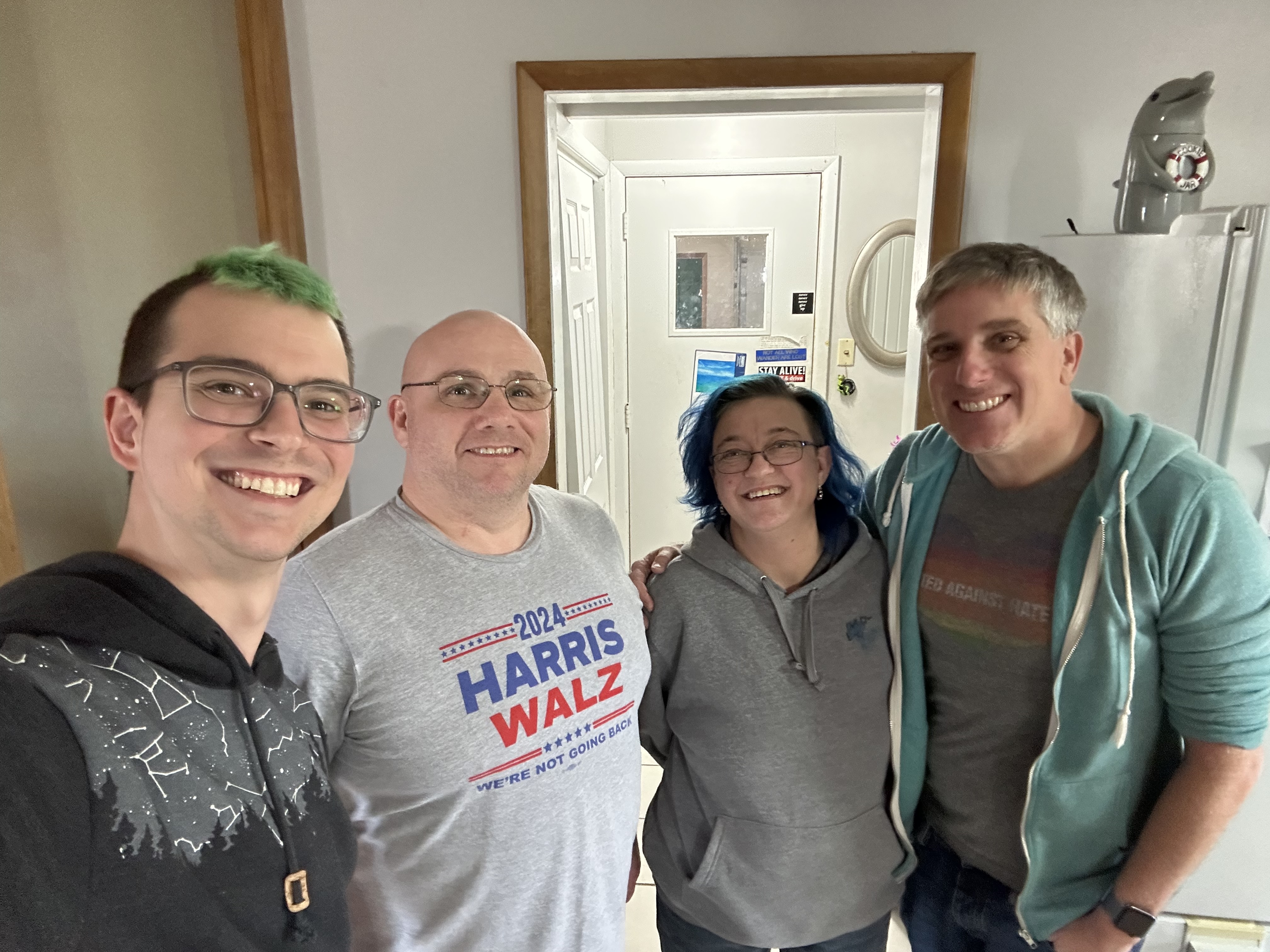 Four people standing in the entryway of a house, posing for a selfie.
