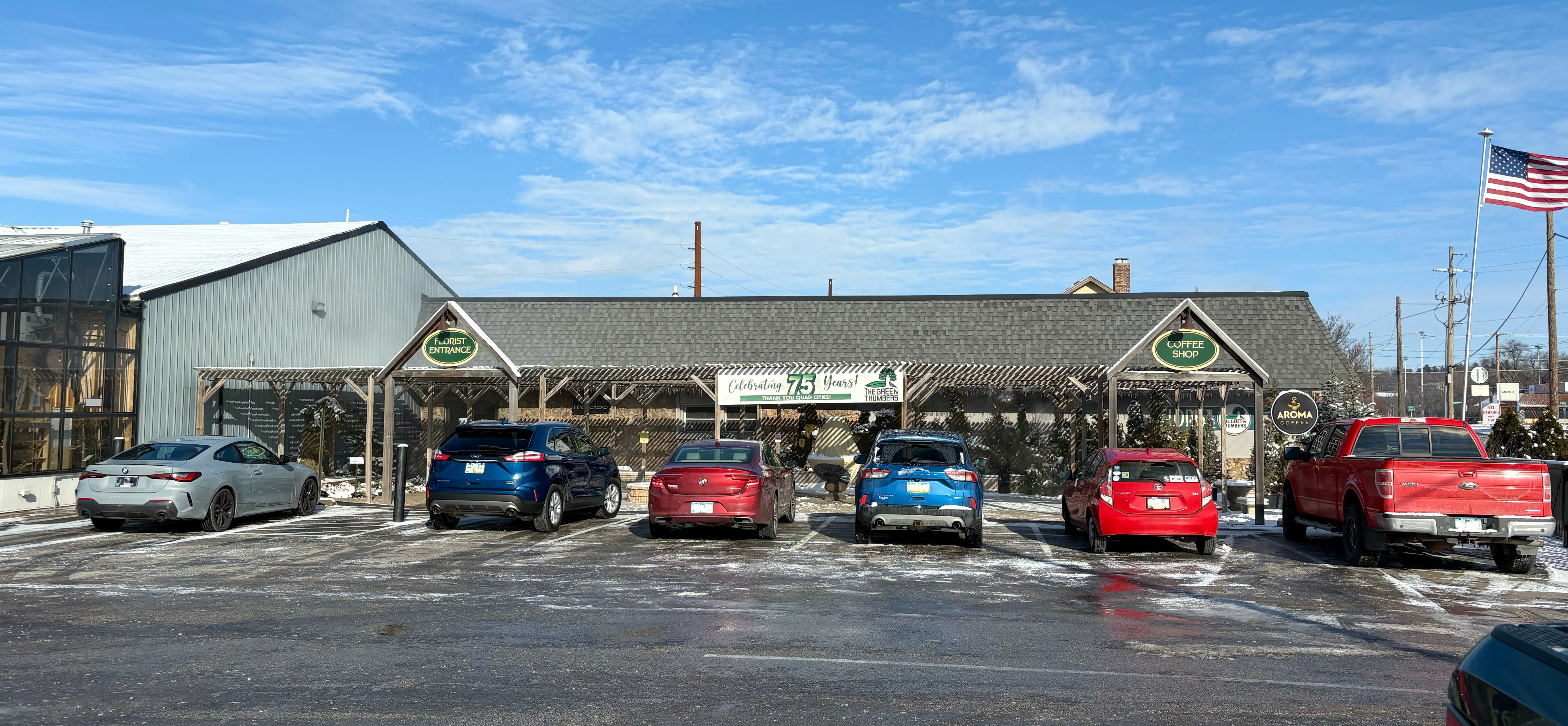 Several cars parked in front of a building with a pergola.
