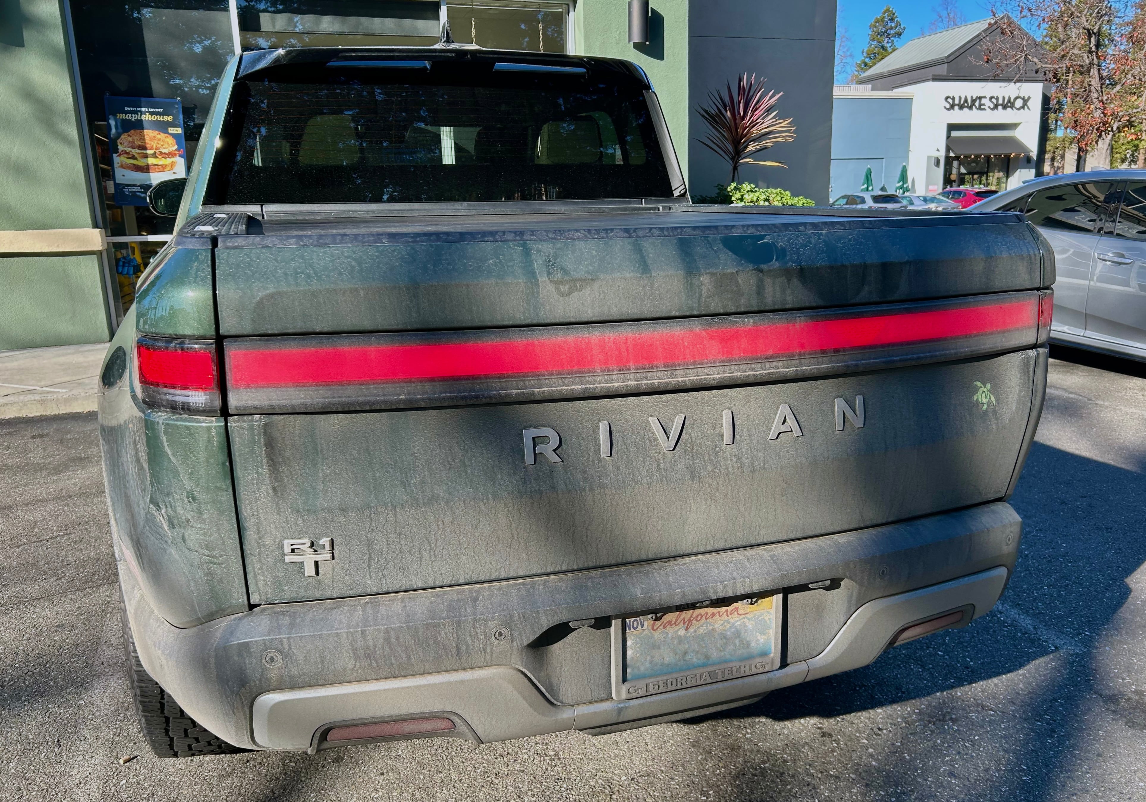 The back of a green truck, looking very gray and brown with dirt. Several smudges are visible on the tailgate.