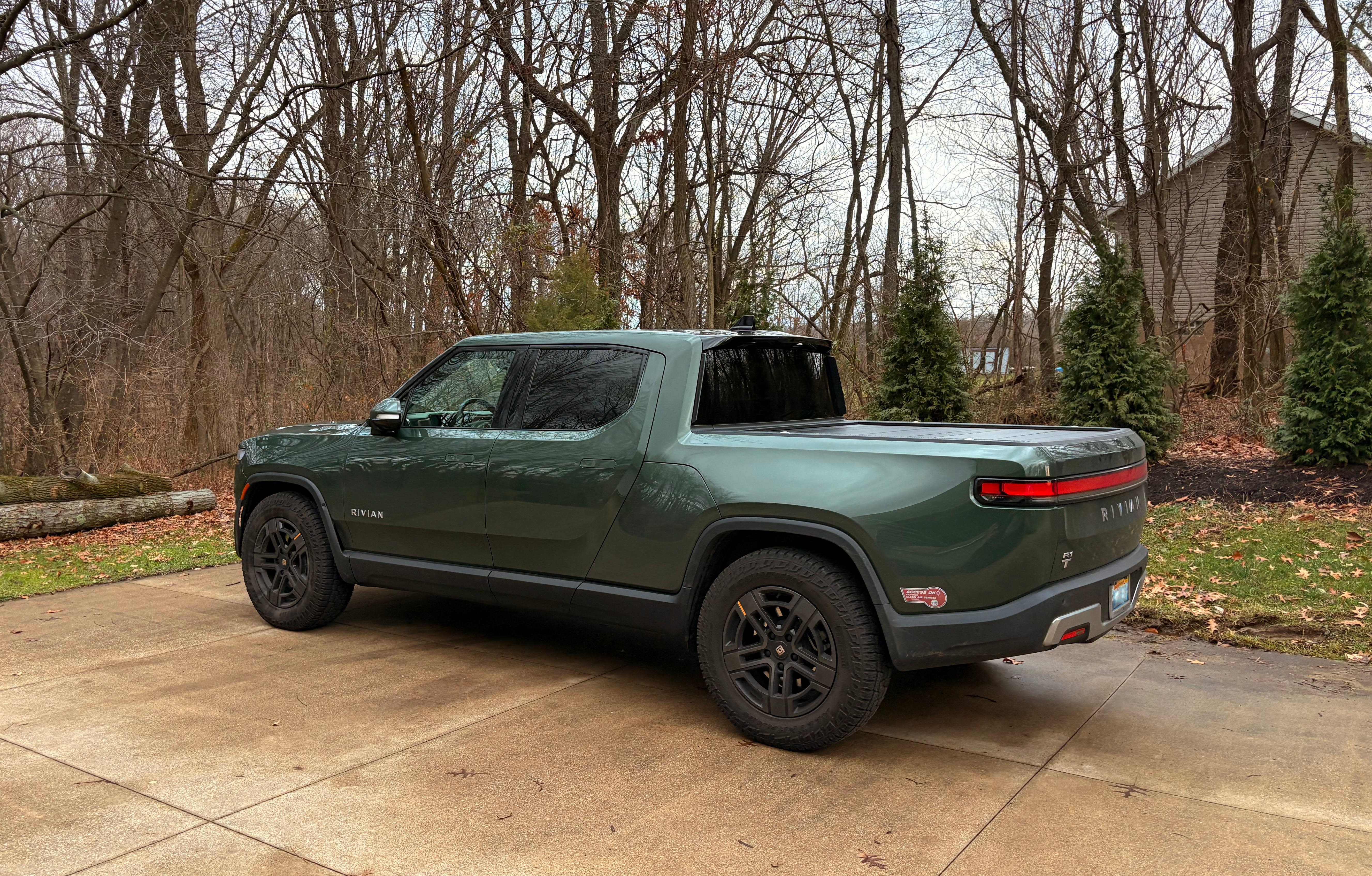 Dark green Rivian truck parked in a driveway.